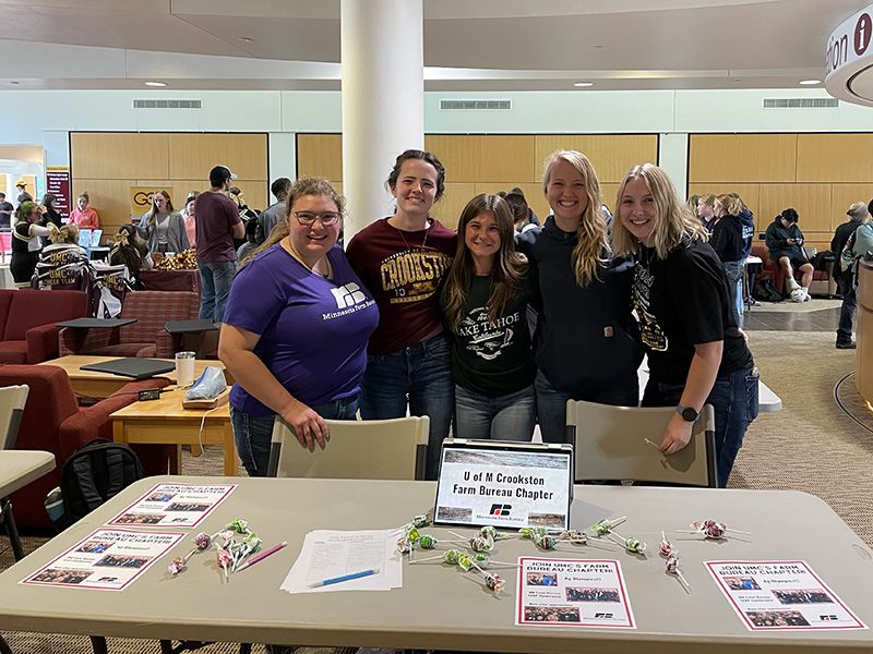 group of five youth standing behind a table